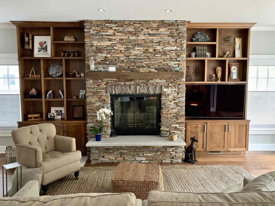 Grand Beach home interior featuring rustic fireplace and built-in entertainment center by Barbour Construction.