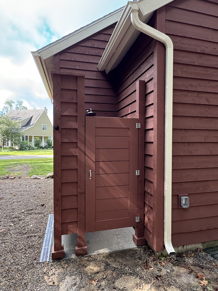 Exterior view of outdoor shower and red siding on custom home by Barbour Construction in Buchanan, MI.