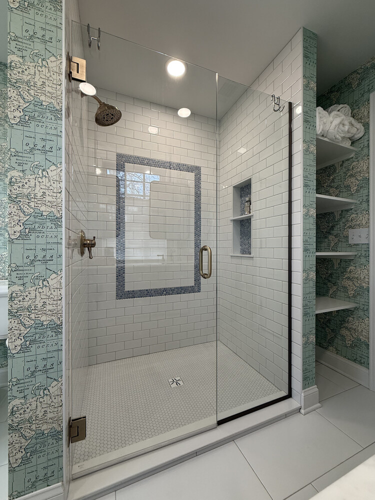 Glass shower with built-in shelving and mosaic tile border by Barbour Construction in South Bend, IN