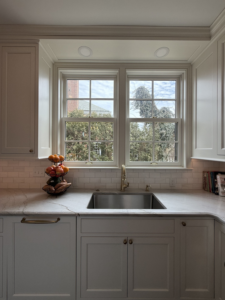 Kitchen sink beneath large double windows with brass faucet by Barbour Construction in South Bend, IN