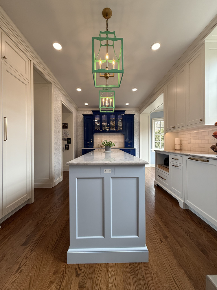 White kitchen island with marble top and built-in outlet in a South Bend home by Barbour Construction