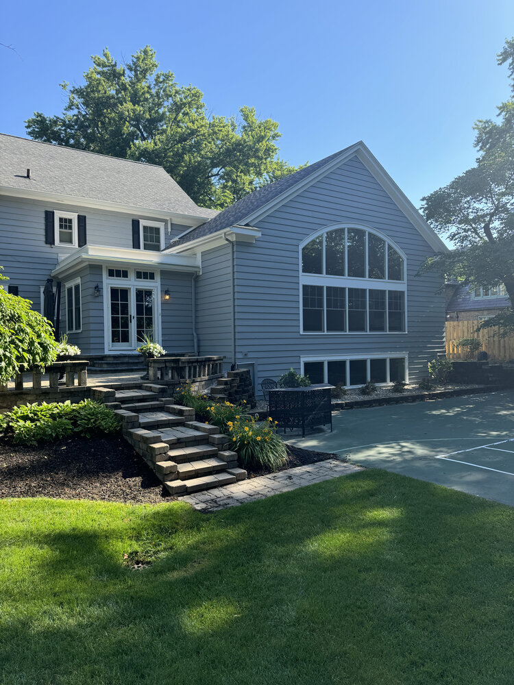 Backyard view of custom-built home with arched window and patio, completed in South Bend, IN by Barbour Construction.