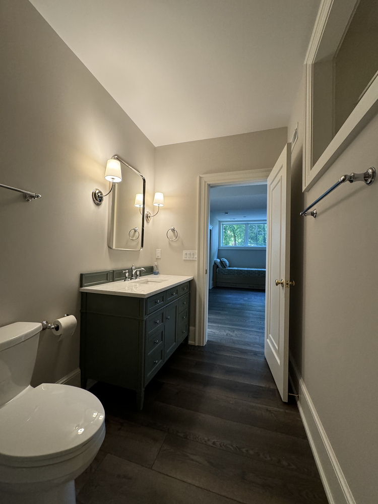 Bathroom entry view with dark flooring and white fixtures in South Bend custom home by Barbour Construction.