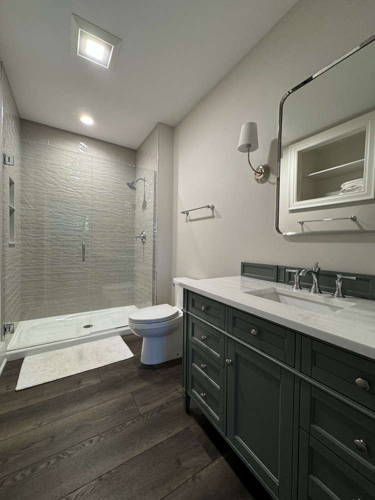 Bathroom remodel in South Bend custom home with green vanity and subway tile shower by Barbour Construction.