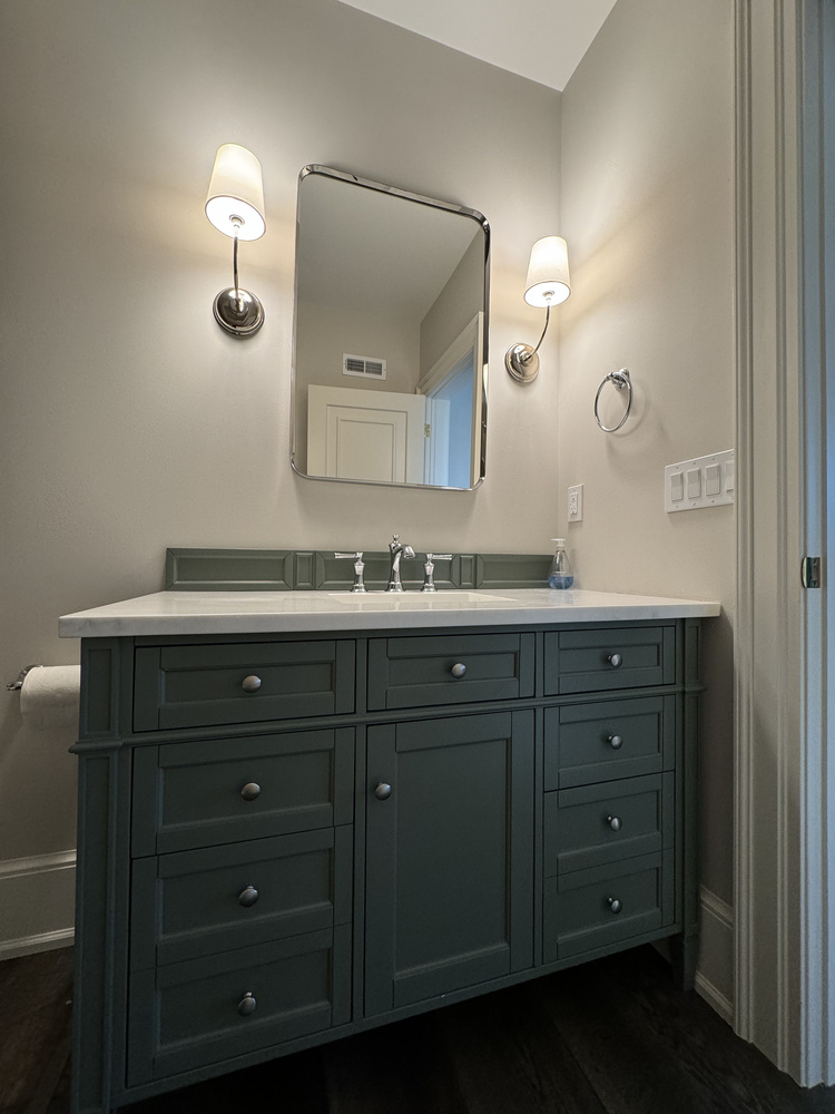 Close-up of custom green vanity with dual wall sconces in South Bend bathroom by Barbour Construction.