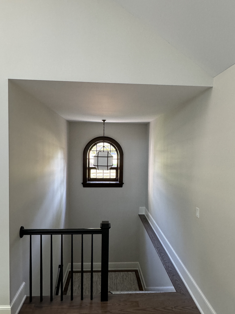 Custom staircase with arched window and pendant lighting in South Bend home by Barbour Construction