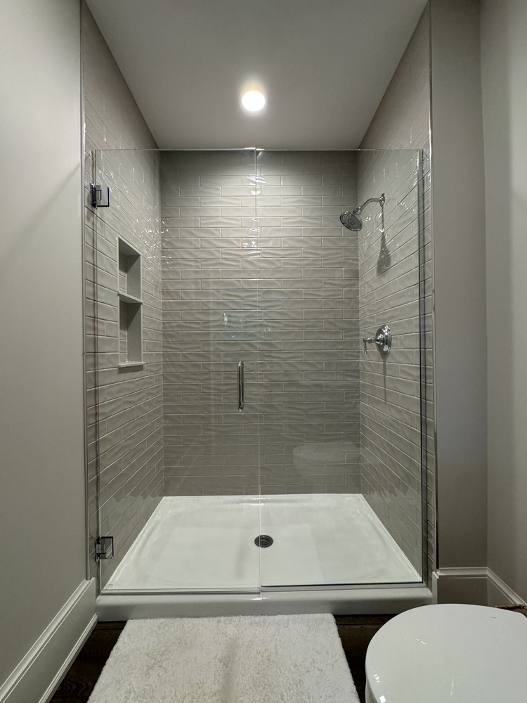 Frameless glass shower with modern tile in custom South Bend bathroom by Barbour Construction.