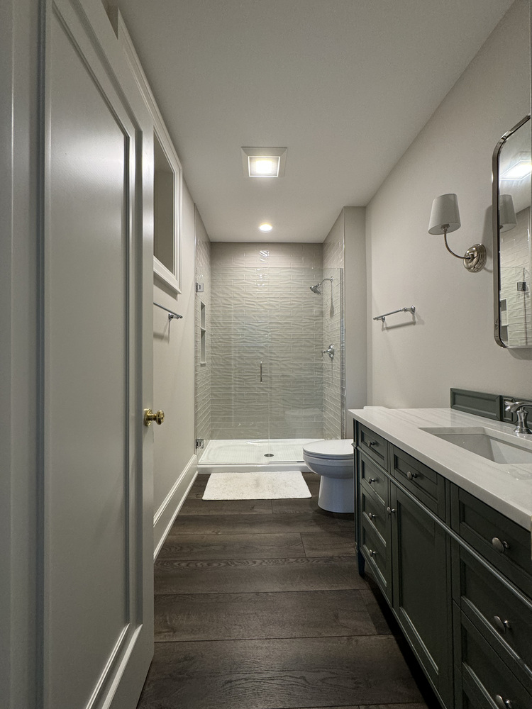 South Bend bathroom renovation featuring green vanity and glass-enclosed shower by Barbour Construction.