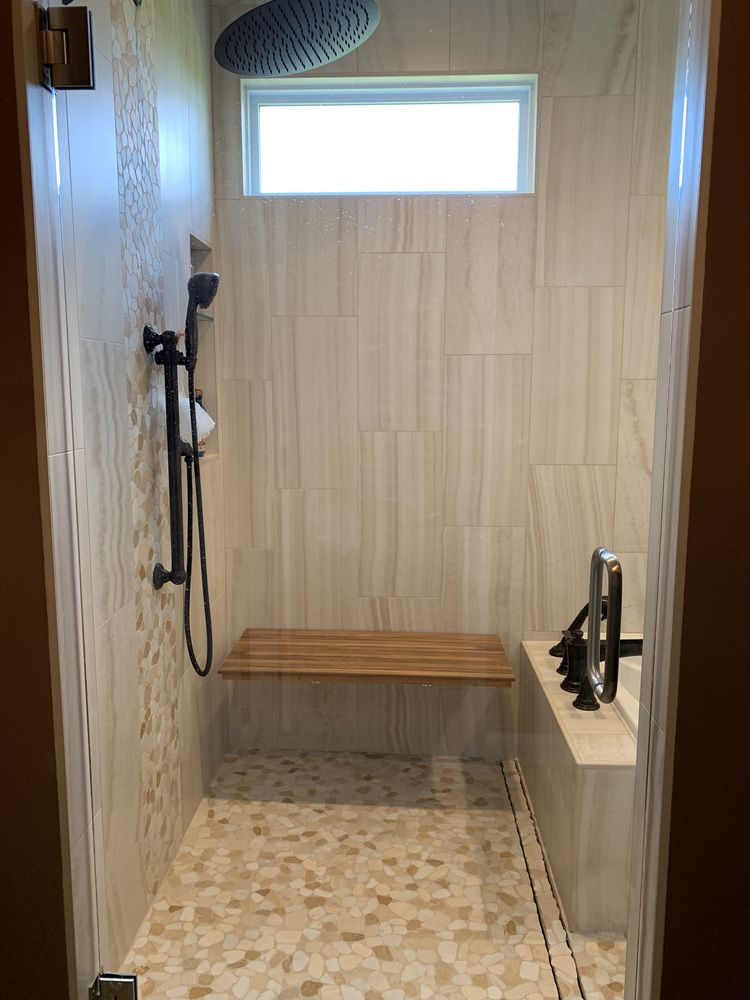 Frameless shower with pebble tile floor and overhead window in South Bend home by Barbour Construction.