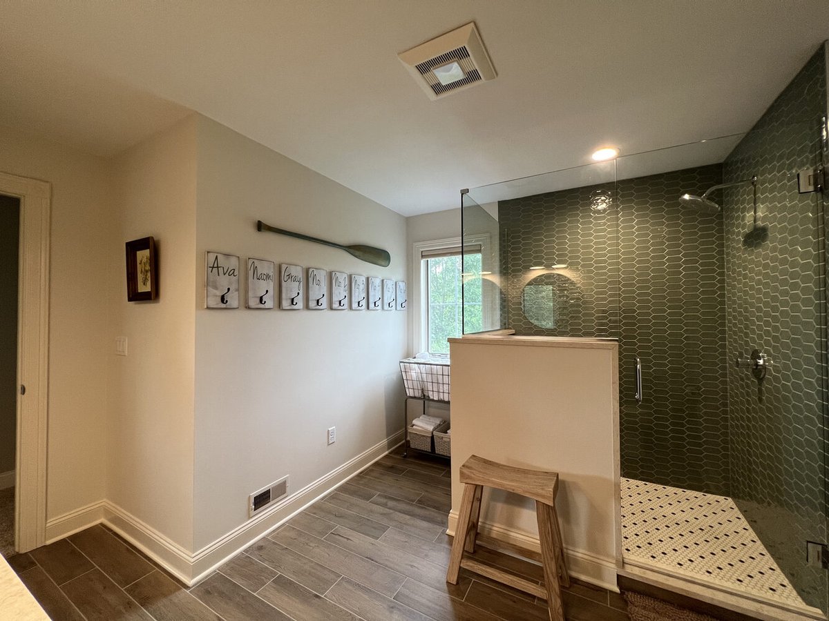 Custom bathroom with green accent shower tile and personalized wall hooks by Barbour Construction in Dowagiac, MI.