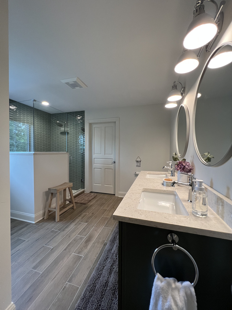 Full view of modern bathroom with glass shower and wood-look tile floors by Barbour Construction in Dowagiac, MI.
