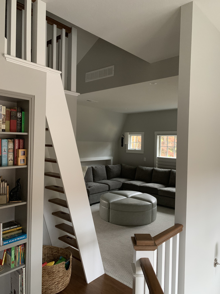 Cozy custom home loft with gray sectional and built-in staircase by Barbour Construction in Grand Beach, MI.