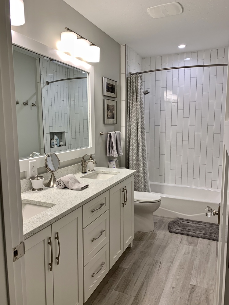 Custom home guest bathroom with dual sinks and vertical subway tile by Barbour Construction in Grand Beach.