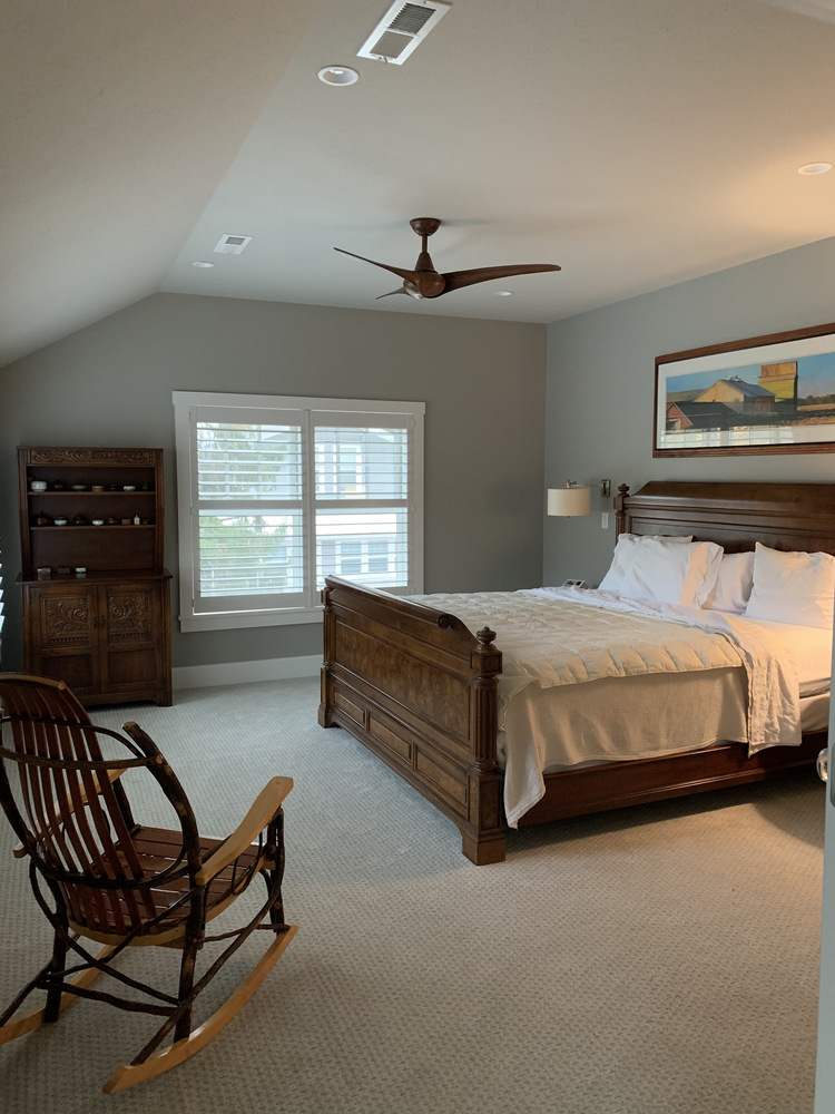 Elegant custom bedroom with wood furniture and ceiling fan by Barbour Construction in Grand Beach, MI.