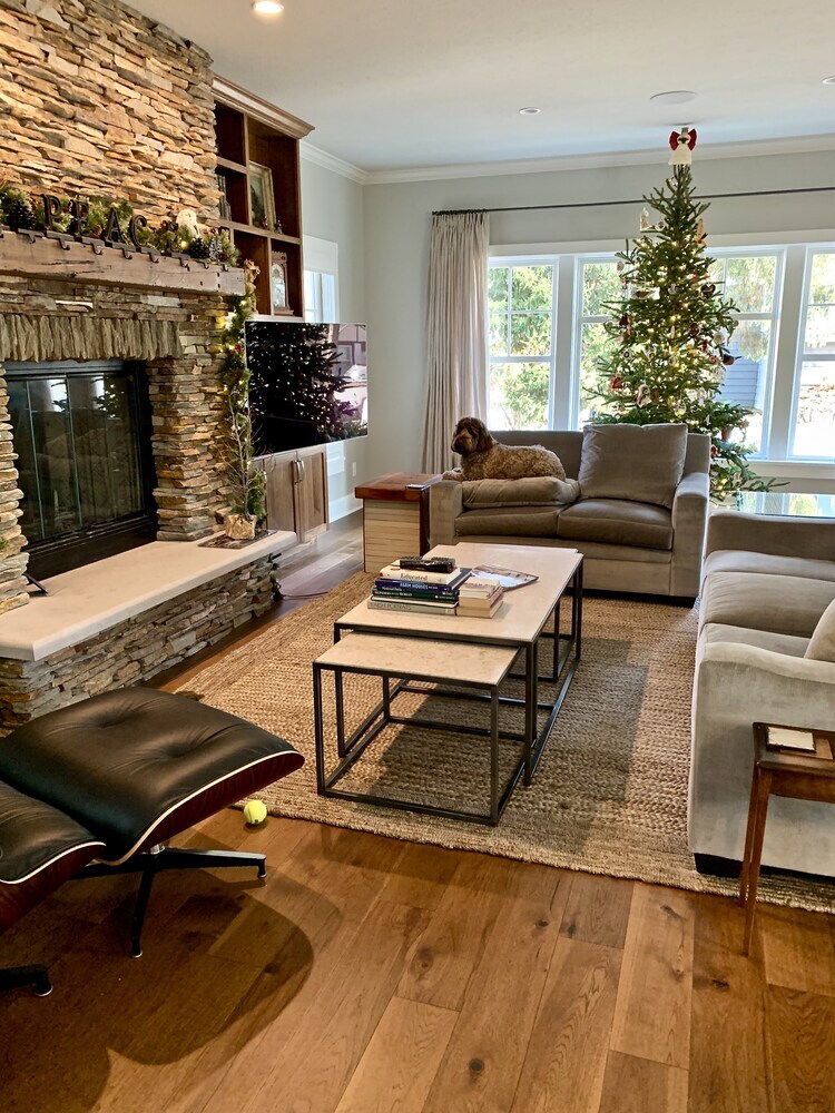 Festive Grand Beach custom home living room with stone fireplace and Christmas decor by Barbour Construction.