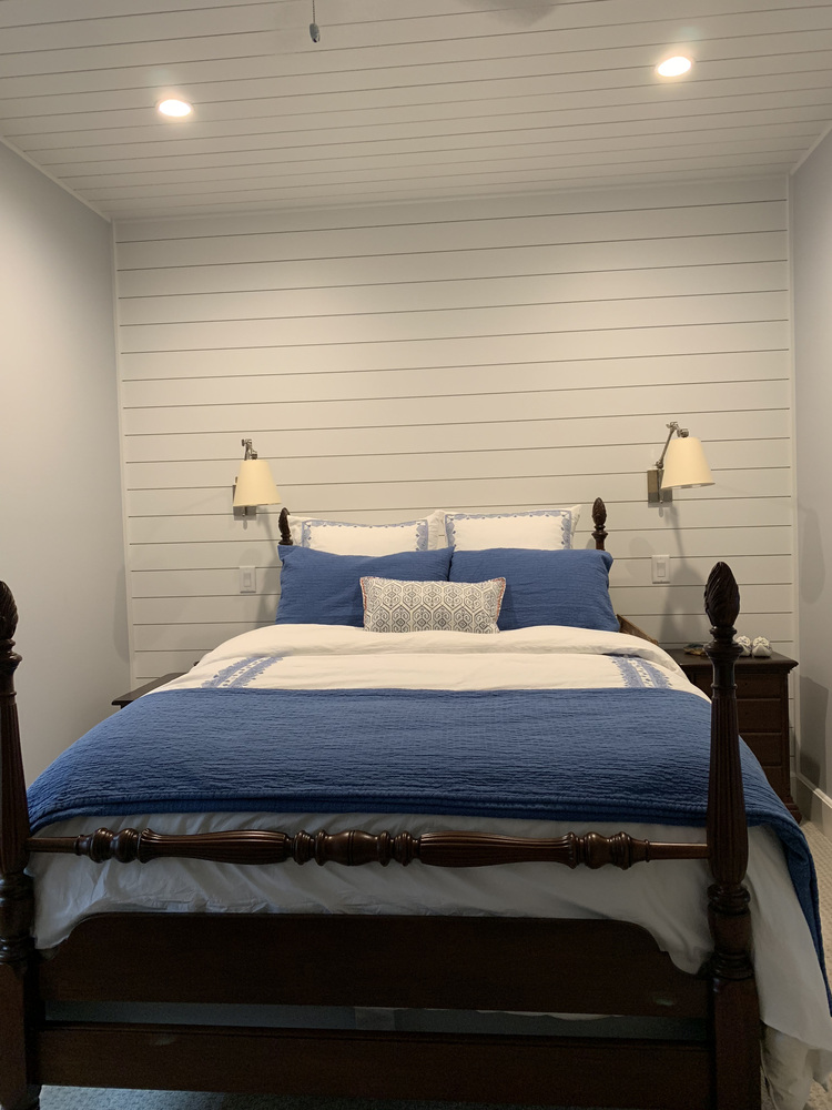 Grand Beach custom home bedroom with white shiplap walls and traditional furniture by Barbour Construction.