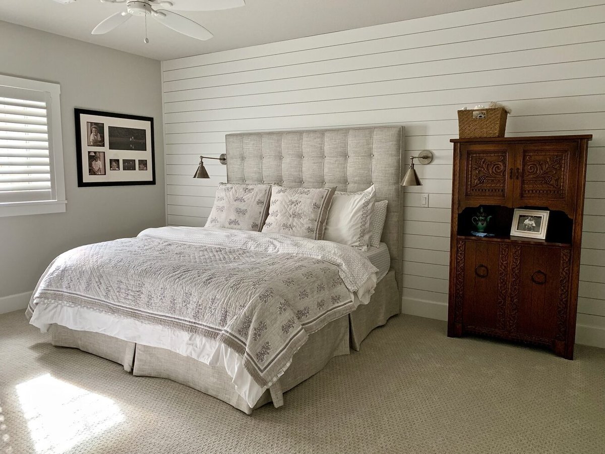 Serene bedroom with upholstered headboard and shiplap accent wall in Grand Beach custom home by Barbour Construction.