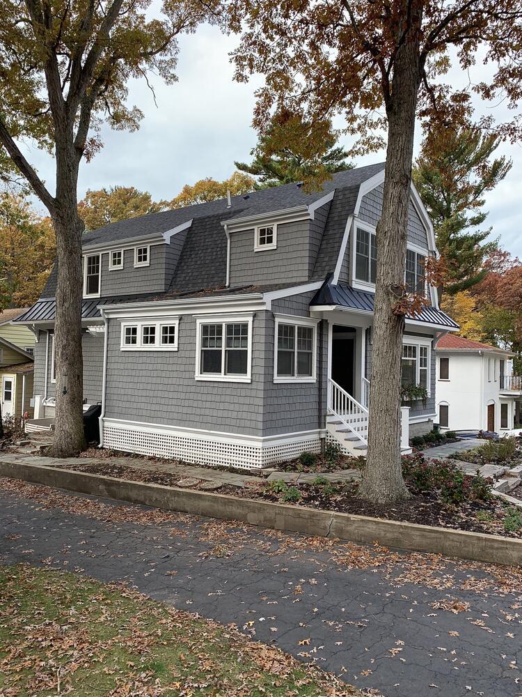 Side view of custom gray-shingled home with white trim by Barbour Construction in Grand Beach, MI.