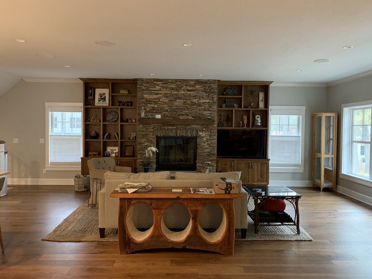 Spacious custom home living room with hardwood floors and rustic fireplace, completed by Barbour Construction in Grand Beach, Michigan.