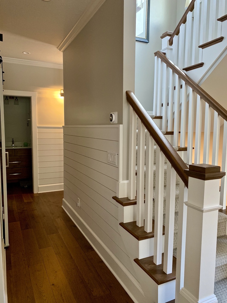 Stairway and hallway with shiplap walls and wood accents in a Grand Beach custom home by Barbour Construction.