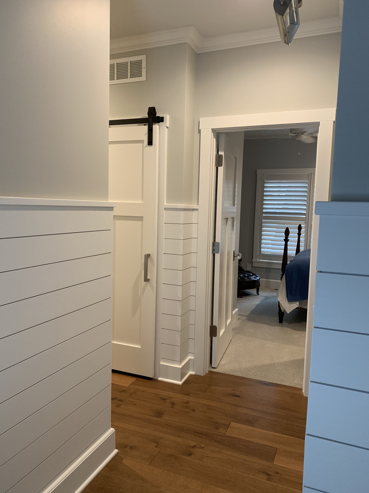 Transitional hallway with shiplap accents and hardwood floors in a custom home by Barbour Construction in Grand Beach.