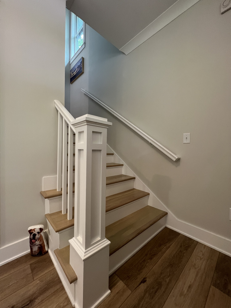 Barbour Construction staircase design with neutral wall tones and wide plank flooring in Grand Beach.