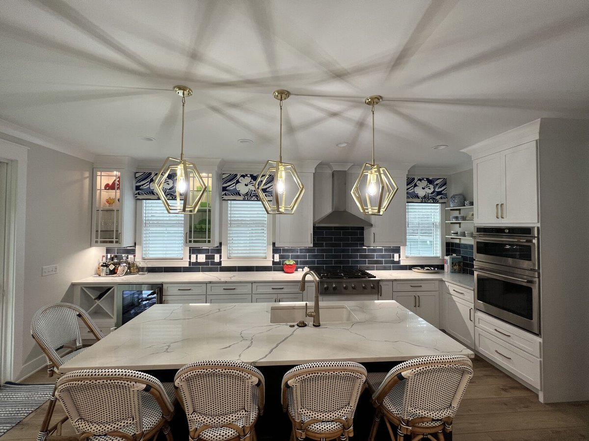 Bright kitchen design with built-in ovens and navy accents by Barbour Construction in Grand Beach.