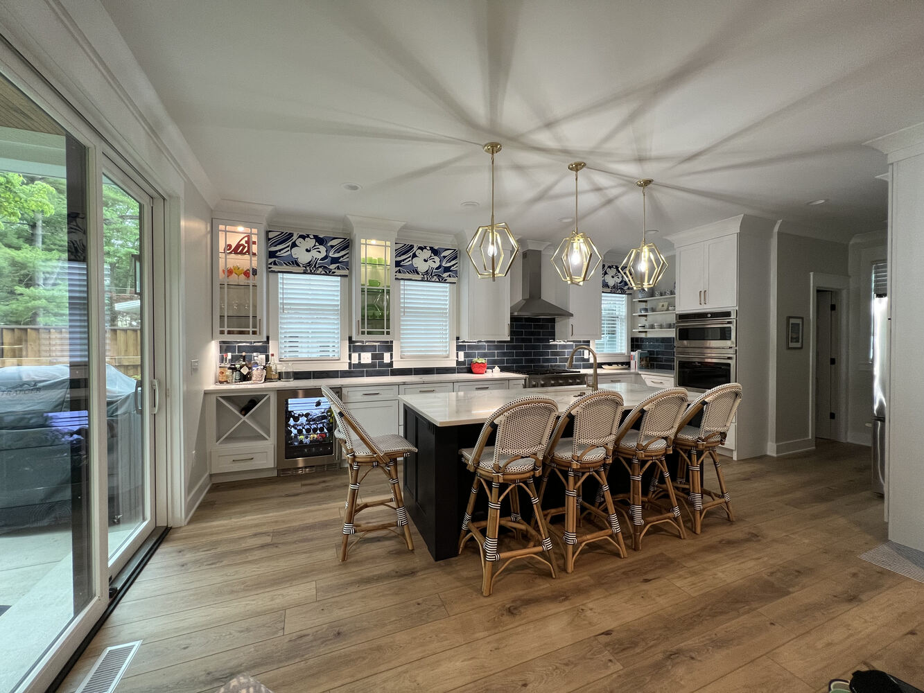 Modern kitchen with hardwood floors and decorative lighting in Grand Beach custom home by Barbour Construction.