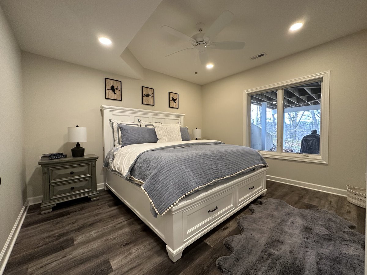 Cozy basement bedroom with white bed frame and wood flooring by Barbour Construction in New Carlisle, IN.