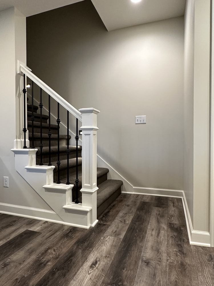 Custom staircase with white trim and dark iron balusters by Barbour Construction in New Carlisle, IN.
