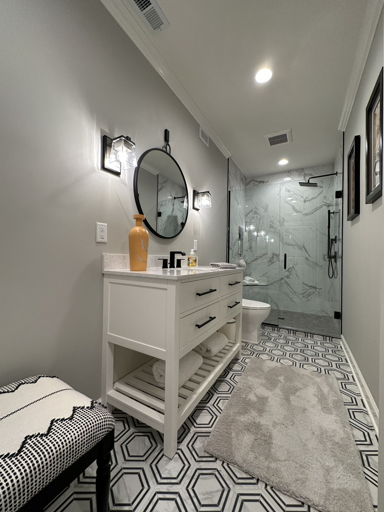 Elegant bathroom with custom vanity and geometric floor tile in New Carlisle home by Barbour Construction.