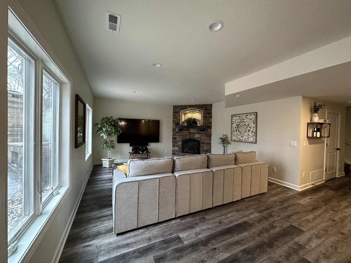 Finished basement lounge with large windows and brick hearth in New Carlisle custom home by Barbour Construction.