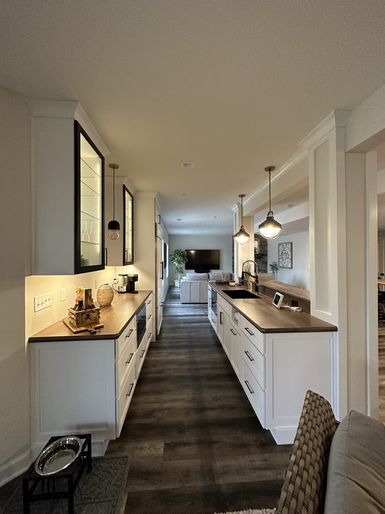 Long galley-style wet bar with custom cabinets and dark flooring by Barbour Construction in New Carlisle.