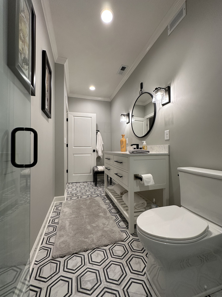 Stylish bathroom with custom vanity, round mirror, and patterned tile by Barbour Construction in New Carlisle, IN.