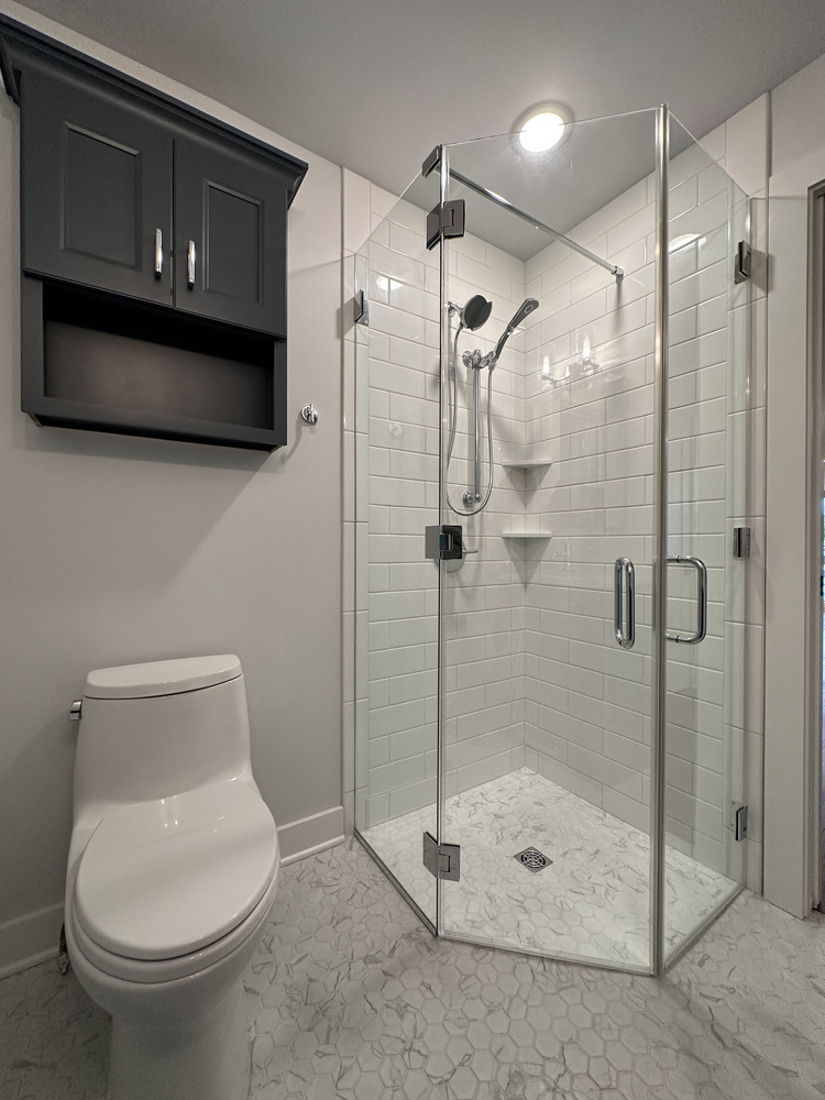 Frameless corner shower with subway tile and sleek fixtures in Sawyer, MI home by Barbour Construction.