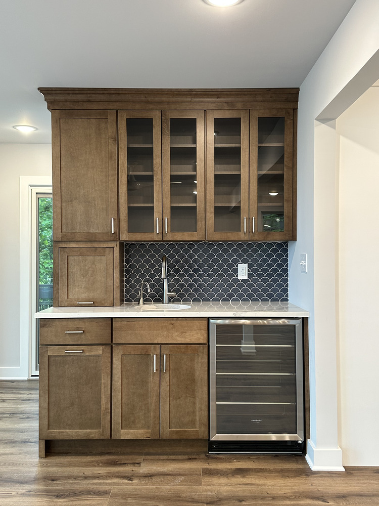 Functional home bar with glass display cabinets and under-counter fridge by Barbour Construction in Sawyer, MI.