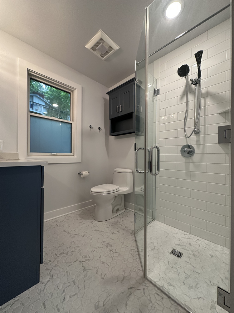 Glass shower with navy cabinet and frosted window in Barbour Construction custom bathroom in Sawyer, MI.