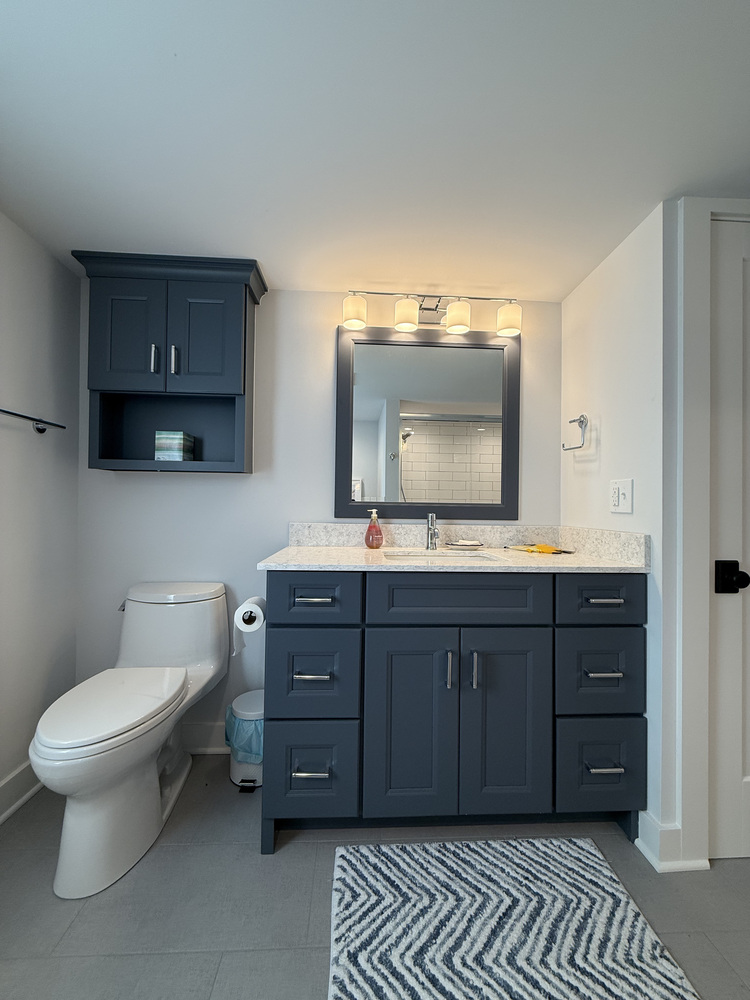Navy blue vanity and wall cabinet with quartz countertop in Barbour Construction bathroom in Sawyer, MI.
