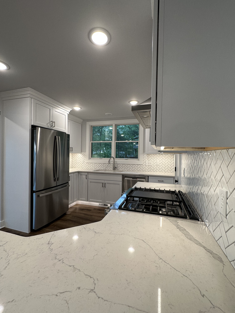 White kitchen with stainless steel appliances and large corner window by Barbour Construction in Sawyer, MI.