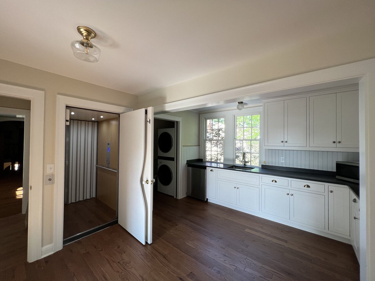 Compact kitchen with open elevator and laundry area in custom Barbour Construction home in South Bend, IN.