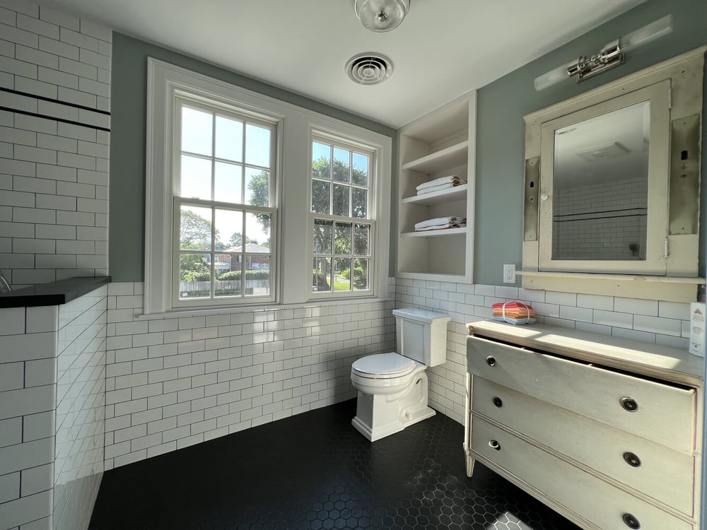 Custom bathroom with vintage vanity and white tile walls in South Bend home by Barbour Construction.
