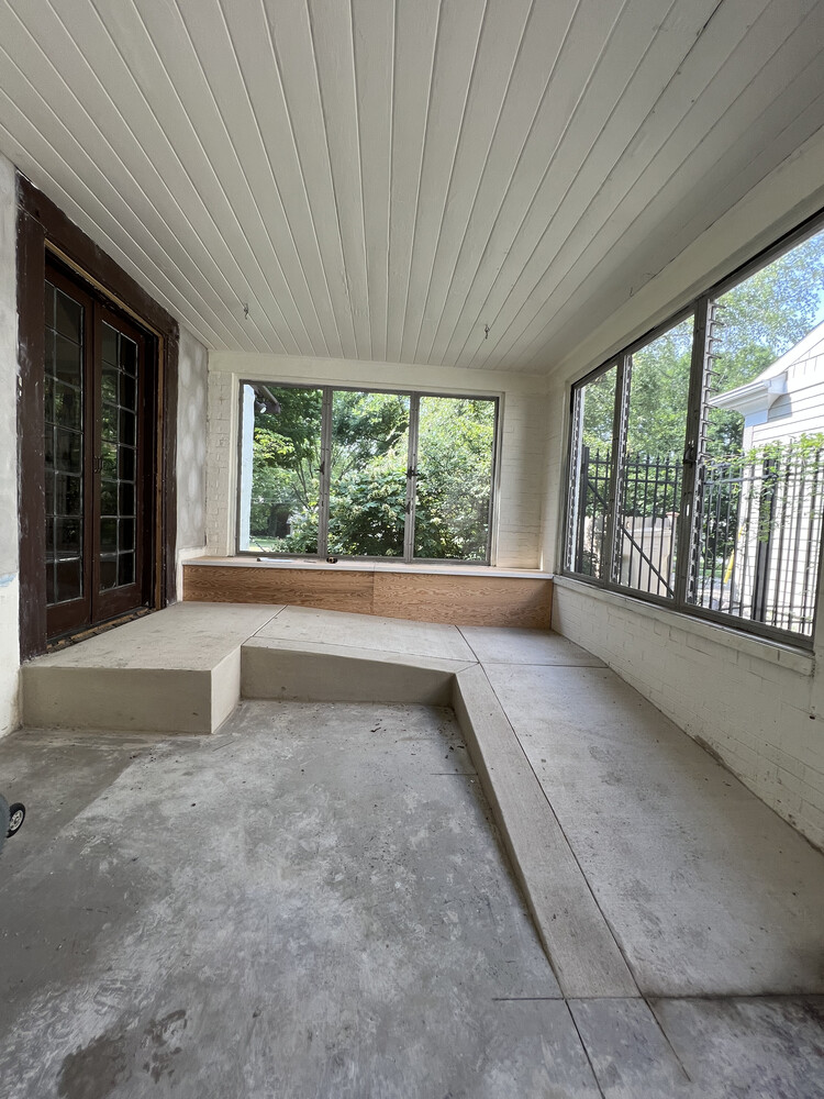 Enclosed sunroom under renovation with tiered concrete platform in South Bend home by Barbour Construction.