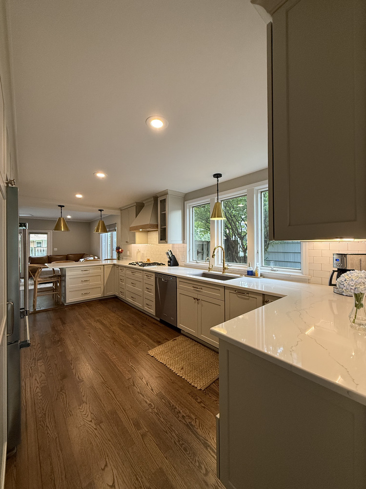 Galley kitchen with large windows and white cabinets in custom South Bend home by Barbour Construction.