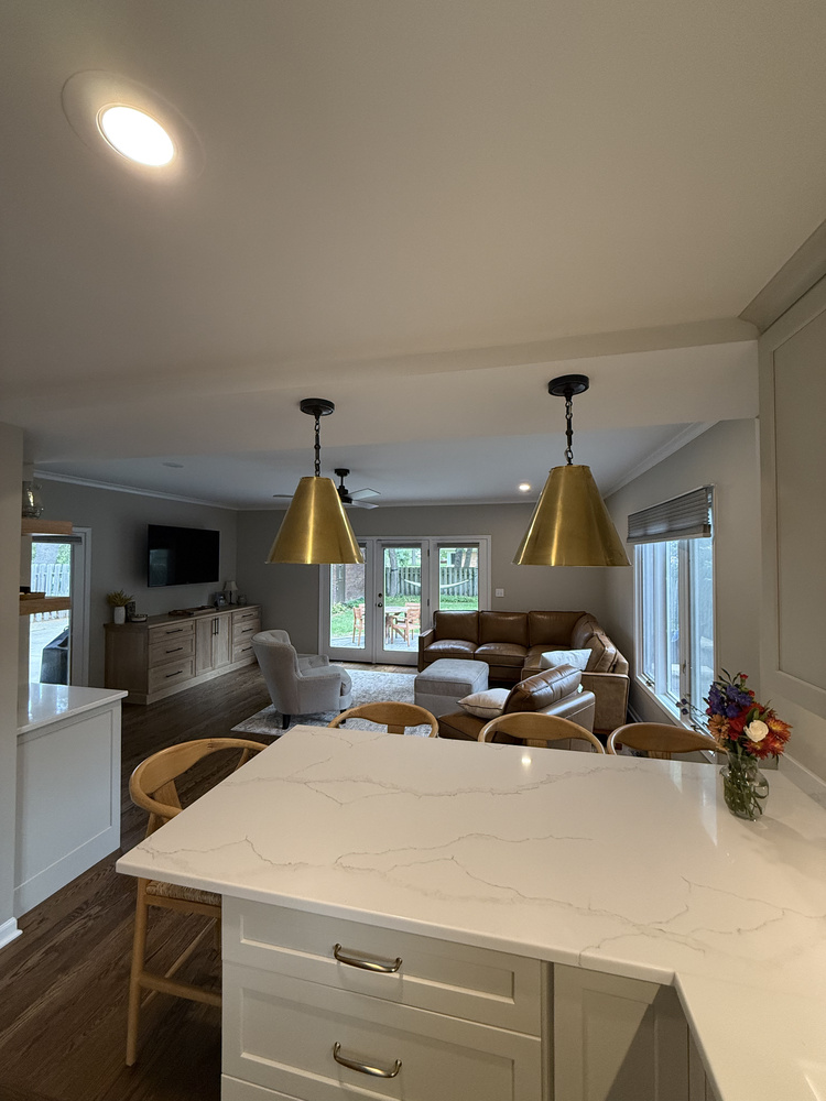 Kitchen island facing living room with gold pendants in Barbour Construction’s South Bend custom home.