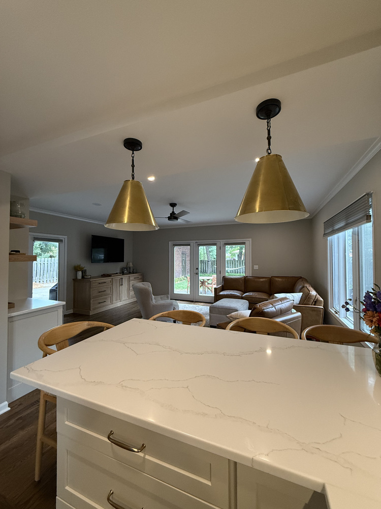View from kitchen island into open living room with pendant lights in South Bend home by Barbour Construction.