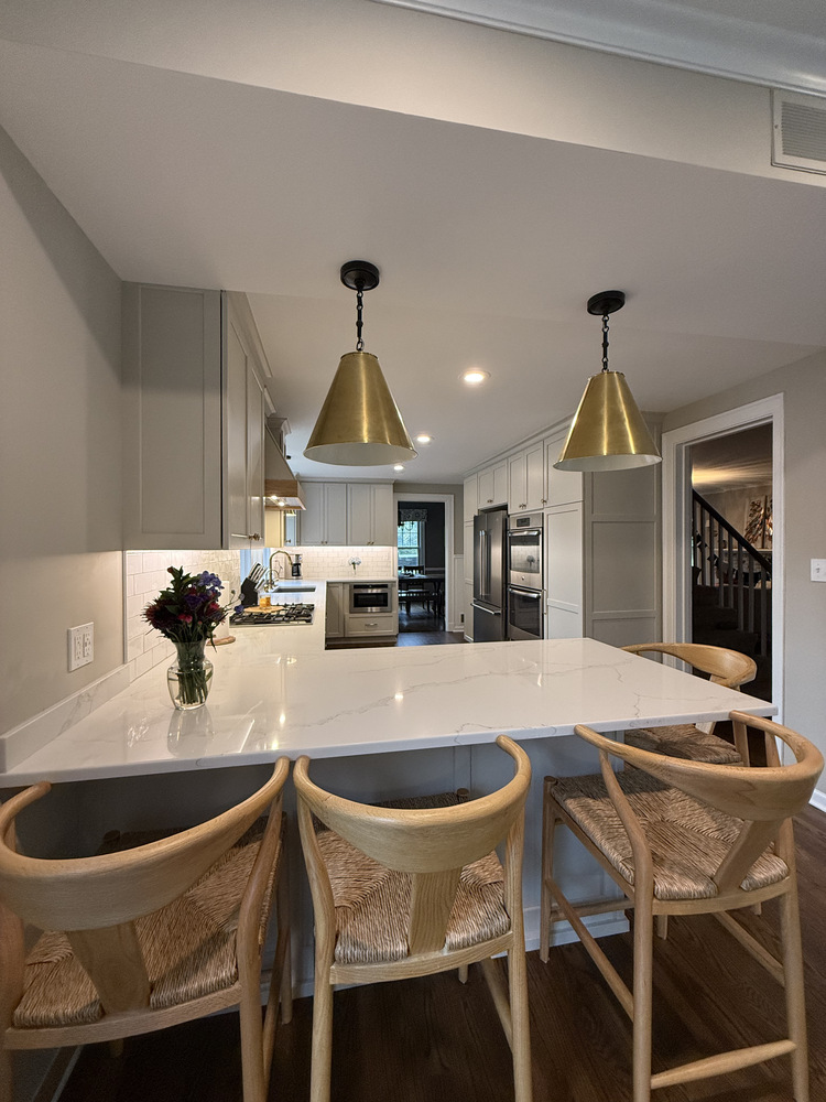 White kitchen island with brass light fixtures and wood barstools in Barbour Construction project in South Bend, IN.