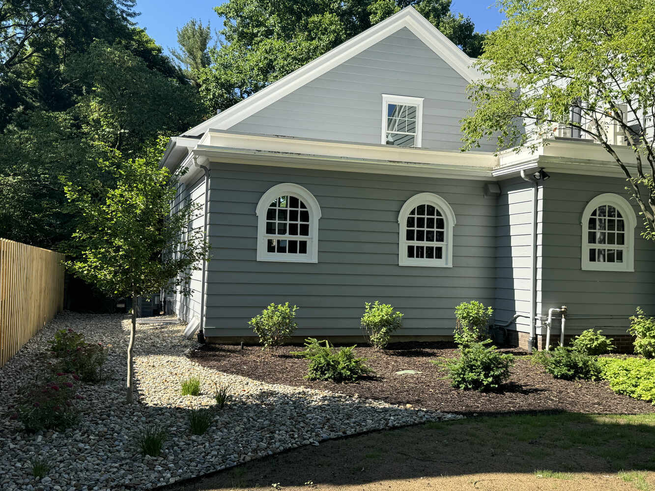 Landscaped side yard with curved stone bed and fresh plantings by Barbour Construction in South Bend, IN.