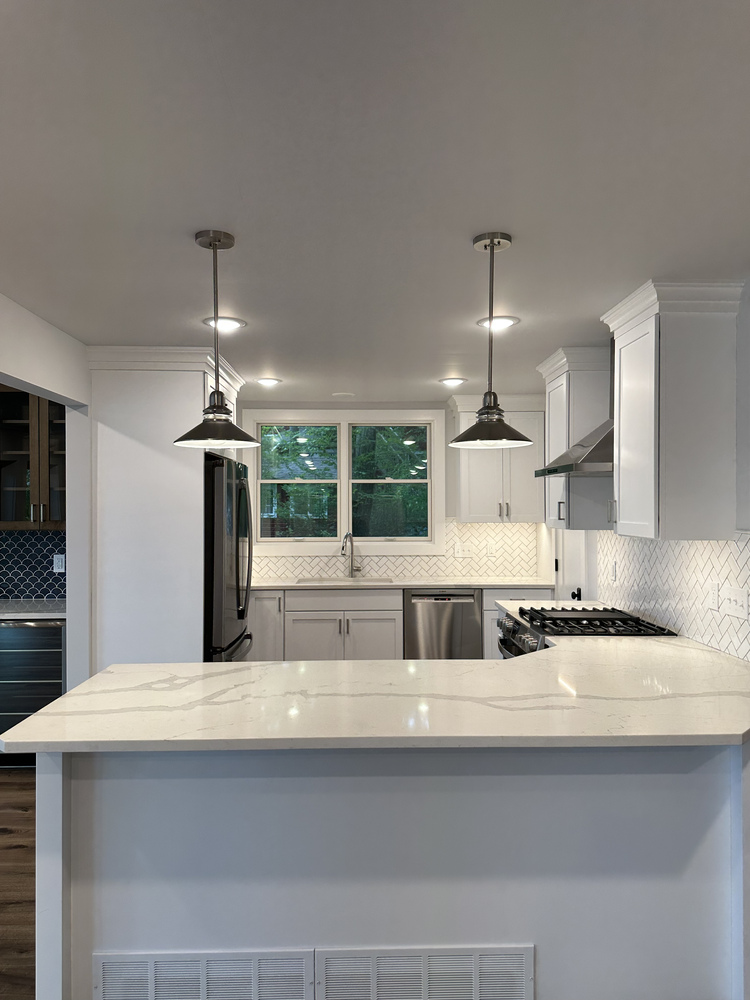 Spacious kitchen with white cabinetry and pendant lighting by Barbour Construction in Sawyer, MI.